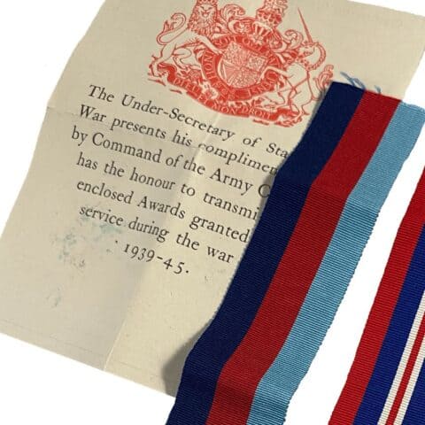 Close-up of the War Office letter transmitting the awards, its red royal coat of arms above the typed text, with two medal ribbons laid across it