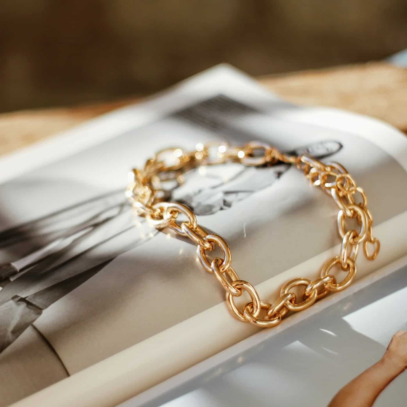 A gold-plated chain bracelet resting on a magazine