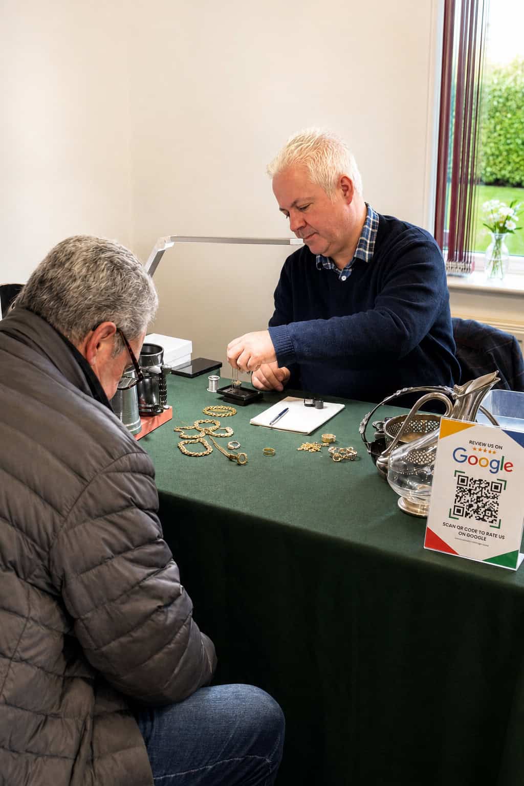 A Cotswold Gold Exchange valuer examining a customer's jewellery one-to-one at a roadshow table